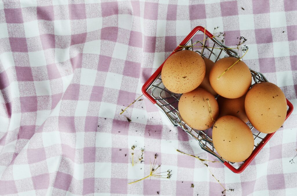 A table with pink cloth and a basket of six eggs.